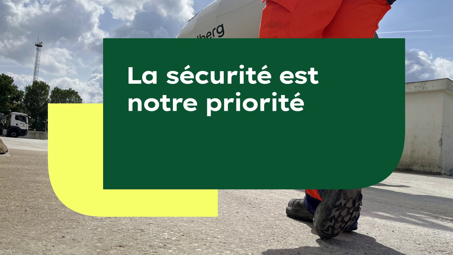 A person in orange safety pants, viewed from behind, walking on a paved industrial site under a partly cloudy sky. Overlaid text on green and yellow geometric shapes reads "La sécurité est notre priorité" (Safety is our priority).
