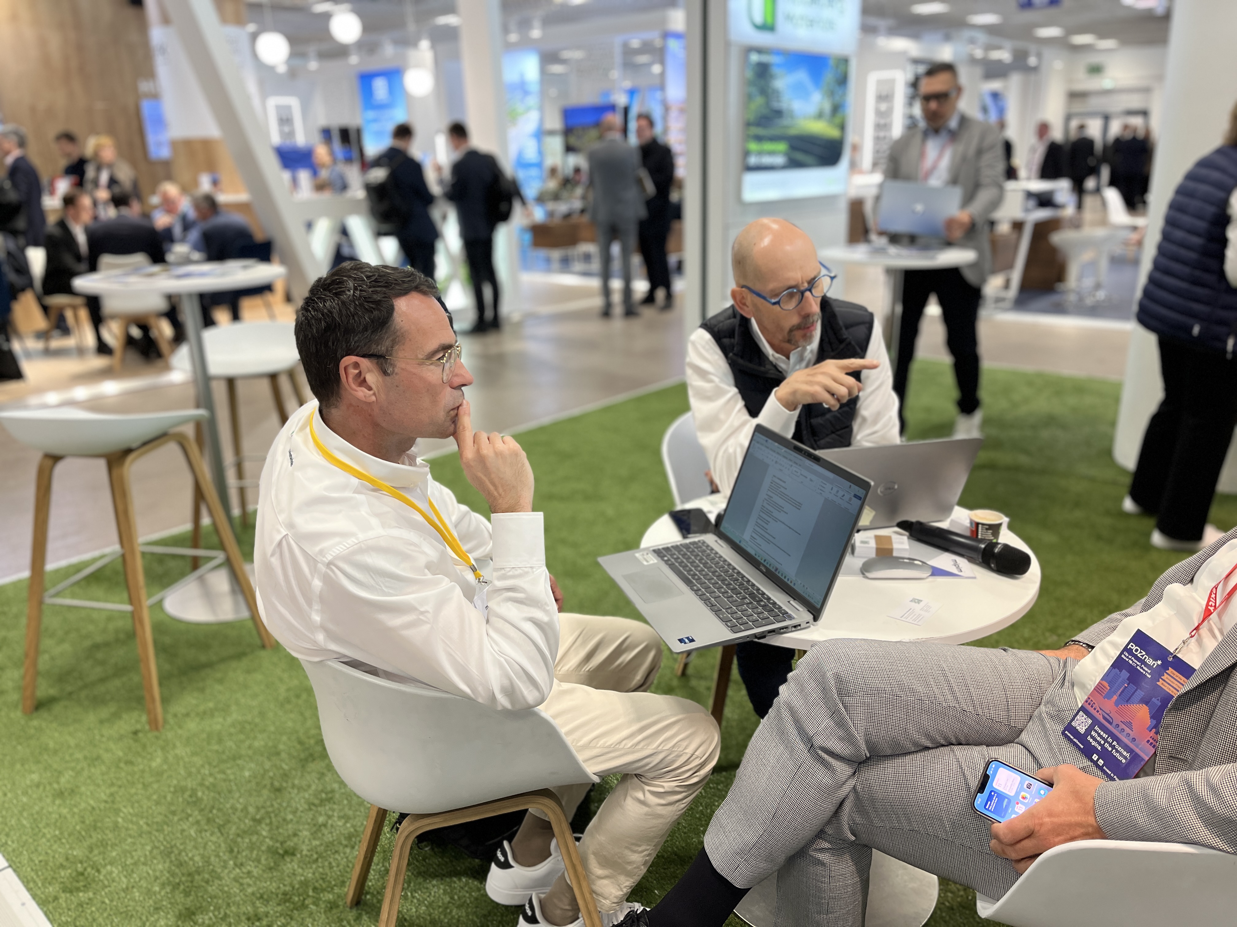 Des personnes discutent autour d'une table avec des ordinateurs portables lors d'un événement professionnel.