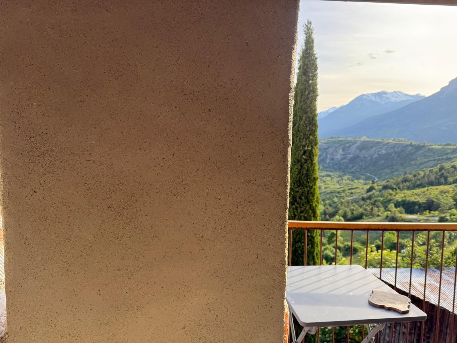 Un mur en béton beige à gauche et une vue sur un paysage montagneux en arrière-plan.