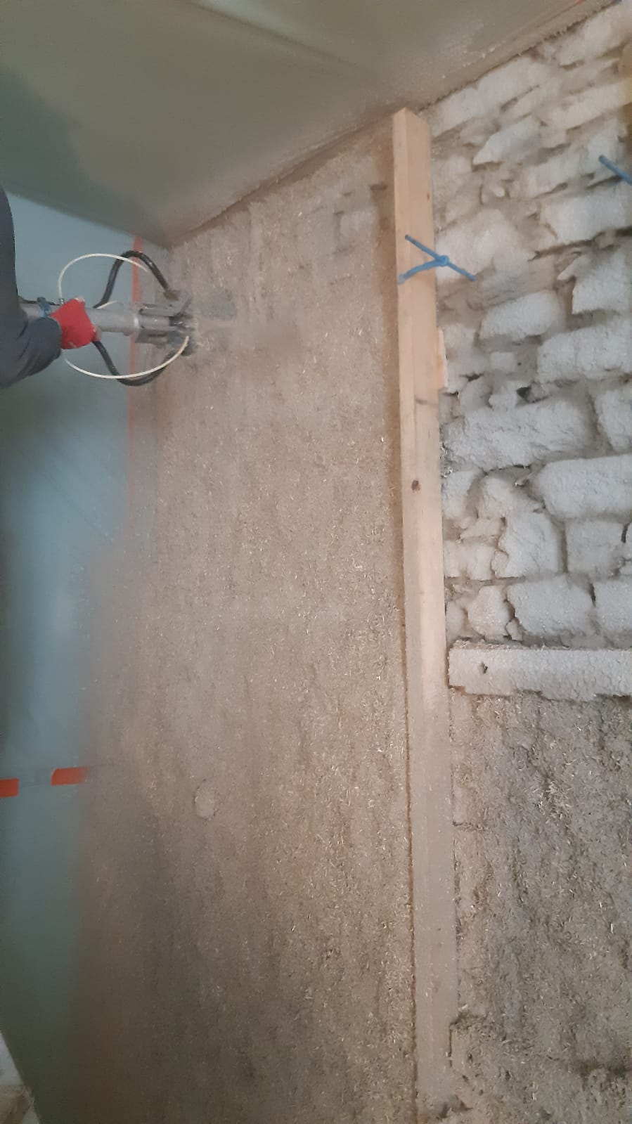 Application d'un mélange isolant sur un mur en briques dans un contexte de construction.