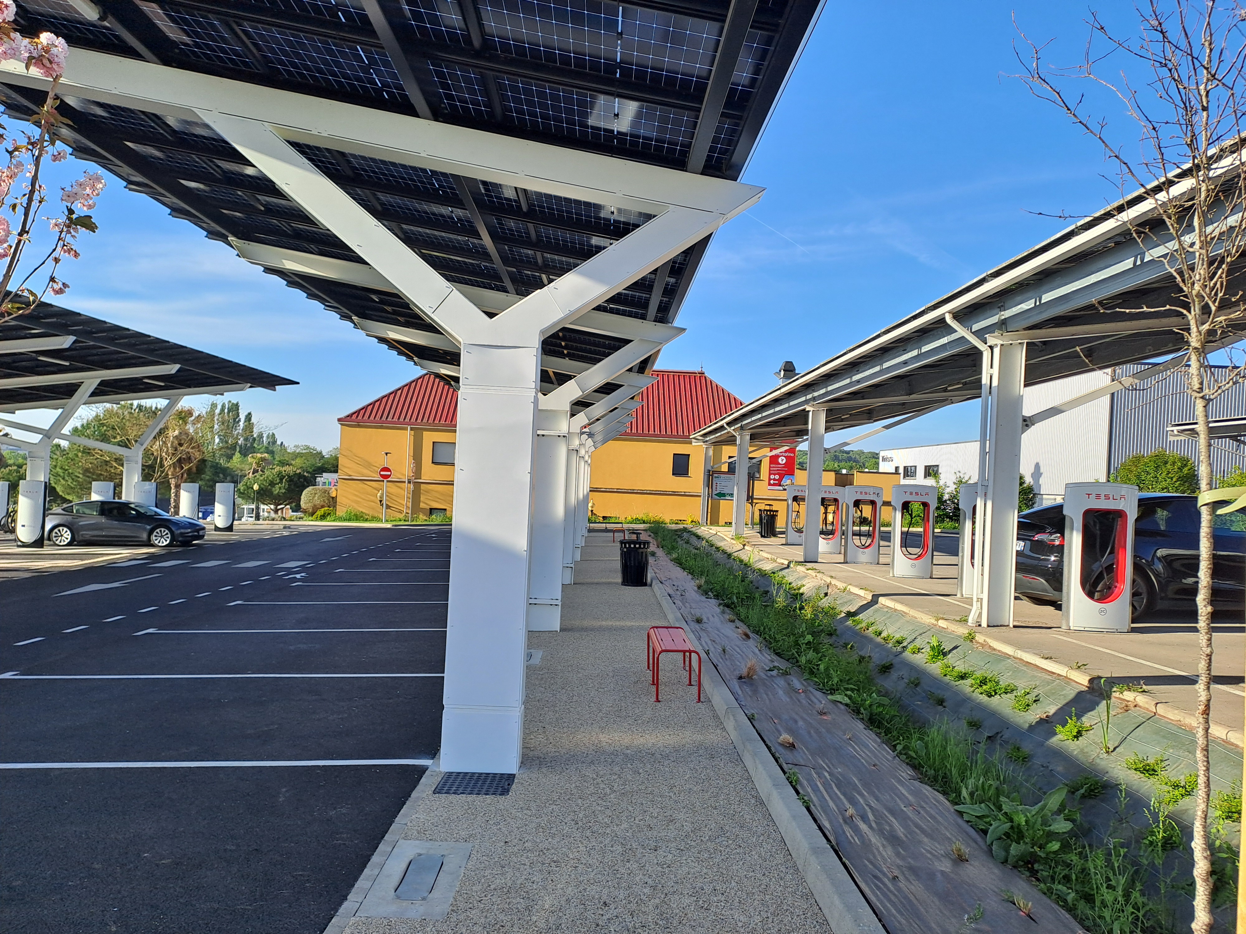 Structure de parking équipée de panneaux solaires avec des bornes de recharge pour véhicules électriques.
