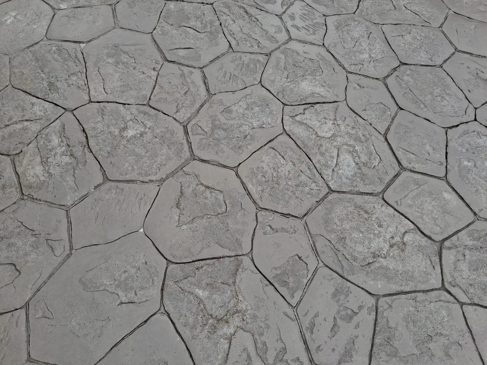 Sol en béton imprimé avec un motif de pierres hexagonales irrégulières.