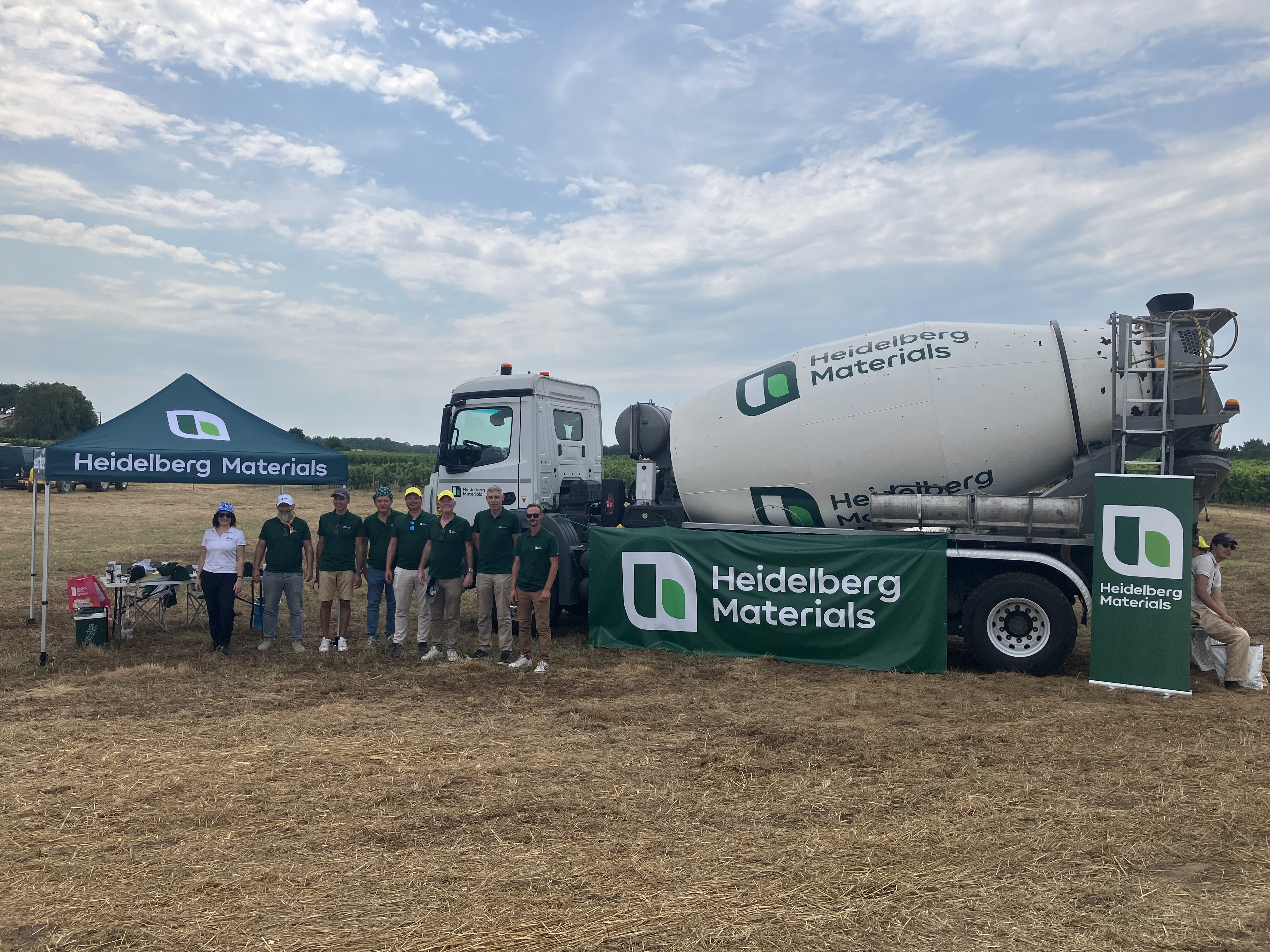Équipe Heidelberg Materials devant un camion-toupie et un stand aux couleurs de l'entreprise lors de la fan zone organisée à Illats à l'occasion du passage du Tour de France 2026.