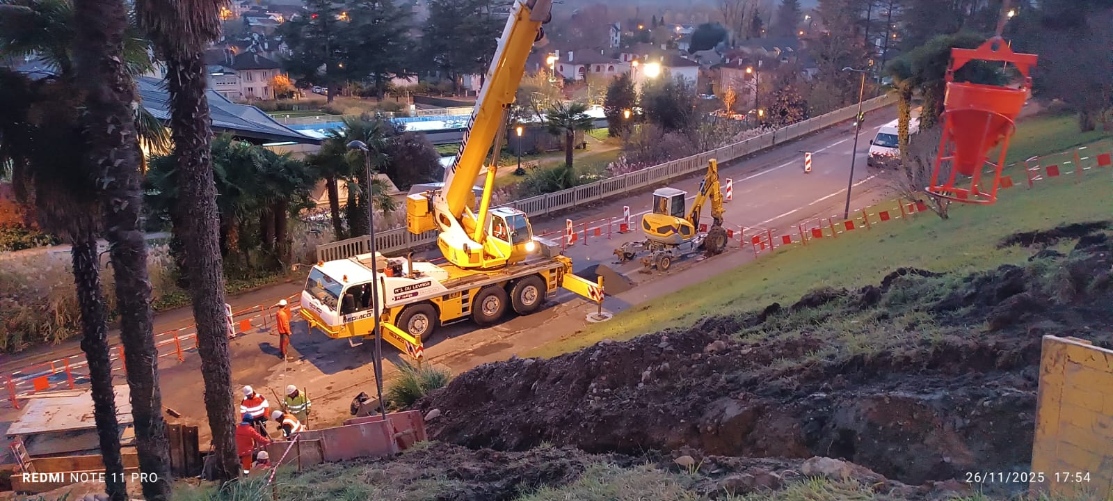 Une grue mobile en action sur un chantier de construction près d'une route.