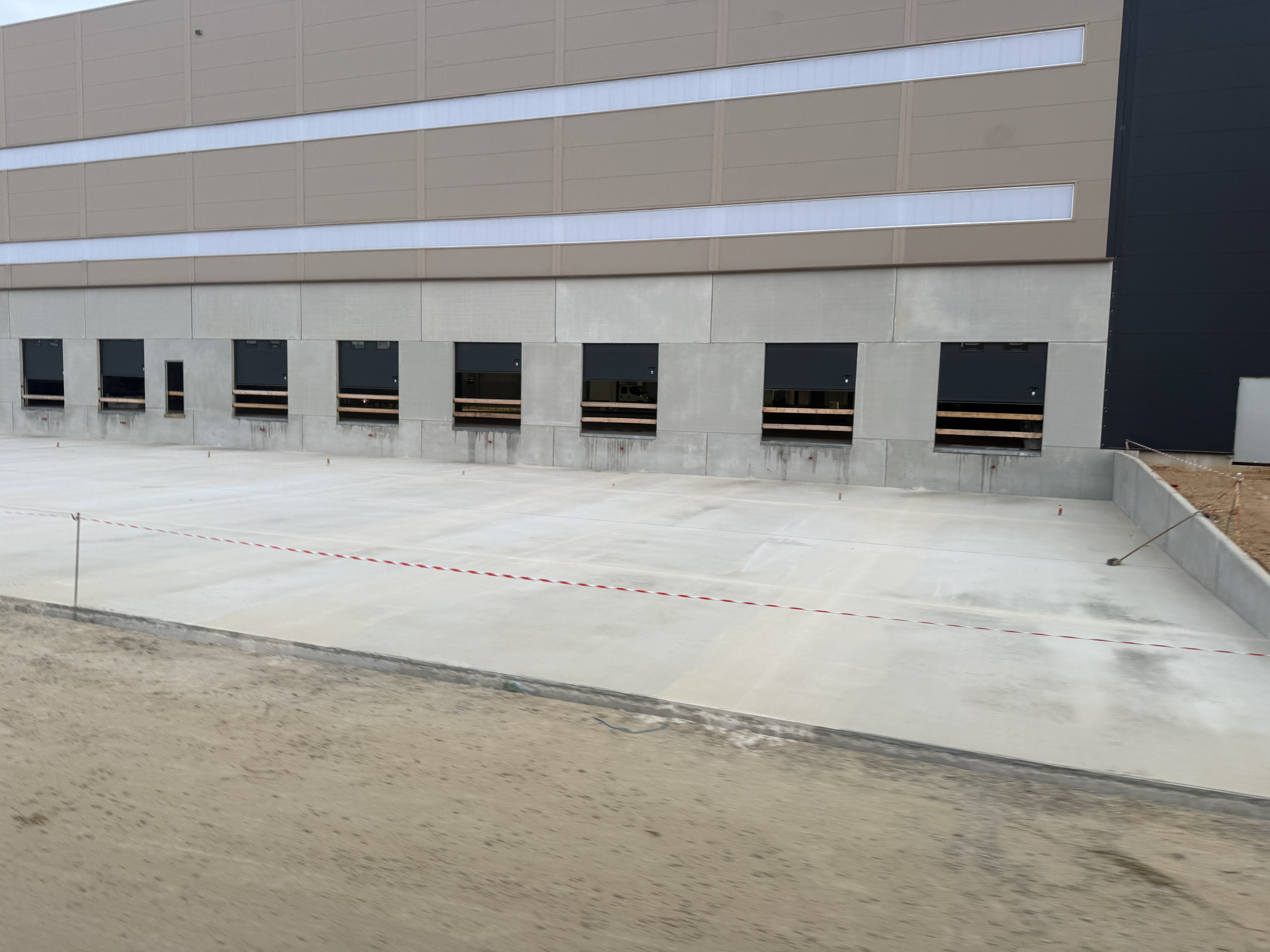 Quais de chargement du futur hub logistique CULTURA à Ferrières-en-Gâtinais, avec dallage en béton et façade de l'entrepôt en cours d'achèvement. Le projet a mobilisé 15 000 m³ de bétons à empreinte carbone réduite EVOBUILD produits par Heidelberg Materials.